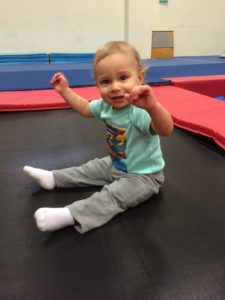 A baby sitting on the ground in an indoor gym.