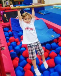 A little boy is jumping in the air over balls.