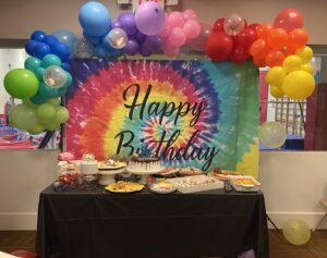 A table with a birthday cake and balloons