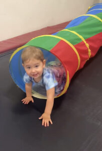 A little boy is playing with a tunnel.