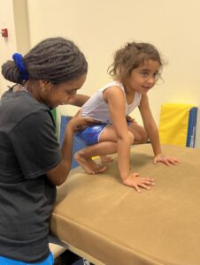 Two girls playing with a cardboard box on the floor.